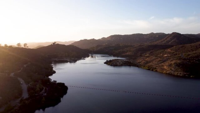 A beautiful aerial shot with a drone flying over Dixon Lake with crystal clear water during golden hour in Escondido, California