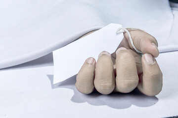 Human corpse covered with a sheet and name tag on hand