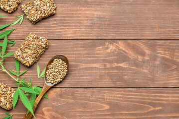 Fototapeta na wymiar Protein bars with hemp seeds, spoon and bush on wooden background