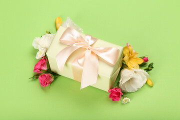 Fototapeta na wymiar Beautiful spring composition with flowers and gift box on green background