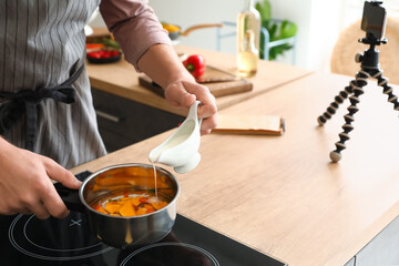 Young man cooking vegetables while following video tutorial in kitchen, closeup
