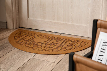Stylish mat near light wooden door in hall