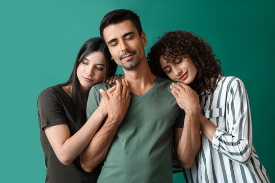 Man and two beautiful women on color background. Polyamory concept