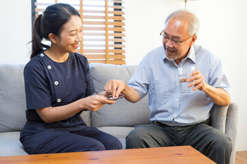 Female asian nurse takes care of sick senior man, help to remind to take a pill.