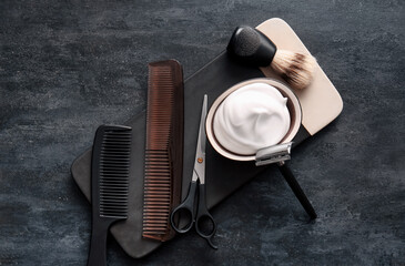 Hair brushes, shaving razor, scissors and foam on black background