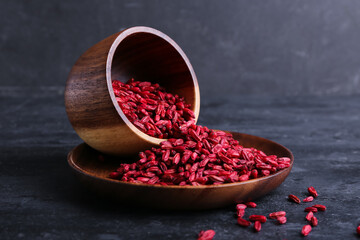 Bowl and plate with dried barberries on dark background