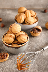 Obraz na płótnie Canvas Bowls of tasty walnut shaped cookies with boiled condensed milk on grey background