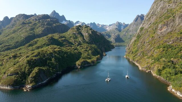 Aerial drone view overlooking two catamarans driving in steep mountain narrows, in Norway