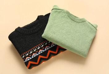Different stylish sweaters on color background