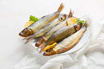 Plate with smoked herring fishes on white background