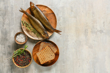 Plate with smoked herring fishes and bread on grey background