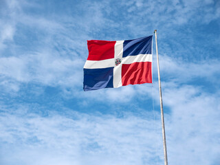 Flying and waving flag of Dominican Republic on wind on sky background