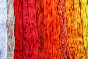 Different colorful embroidery threads as background, top view