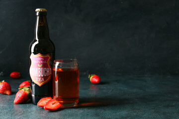 Bottle and glass of fresh strawberry kombucha on dark background
