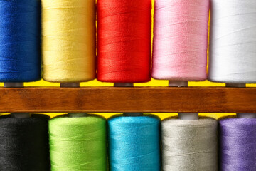 Closeup view of spools with sewing threads on yellow background