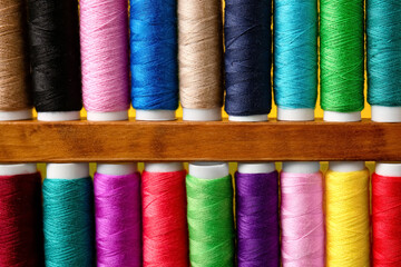 Spools with sewing threads on yellow background, closeup