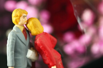 Miniature figure couple model toy put in front of flower background scene.