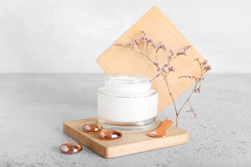 Jar with natural cosmetic cream and plant branch on light background