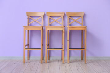 Wooden chairs near violet wall in room