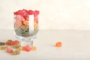 Glass with different jelly bears on light background