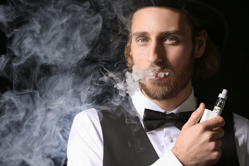 Vaping young man on black background
