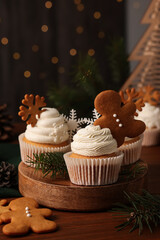 Different beautiful Christmas cupcakes and fir branches on wooden table. Space for text