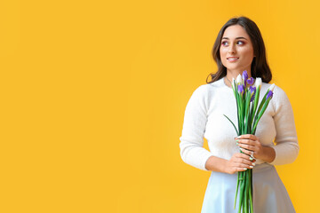 Woman holding iris flowers and looking aside on yellow background. International Women's Day