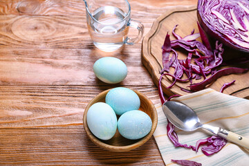 Bowl with natural dyed Easter eggs and purple cabbage on wooden table