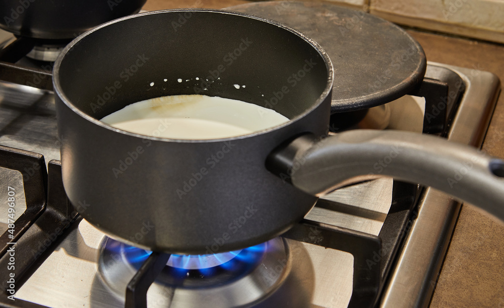 Canvas Prints Cream is cooked in saucepan on gas stove to make cake