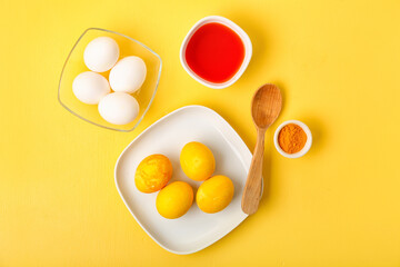 Easter eggs, turmeric powder and bowl with homemade natural dye on color background