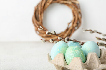 Holder with beautiful Easter eggs and willow branches on light background, closeup