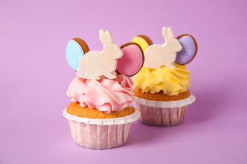 Tasty Easter cupcakes on purple background, closeup