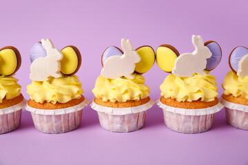 Tasty Easter cupcakes on purple background, closeup