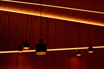 Lamps on long wires in front of of a wooden stripes wall, elements of lighting and interior design.