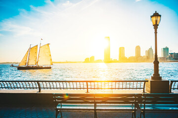 New York travel scenery view from lower Manhattan towards New Jersey at sunset. Boat sailing on...