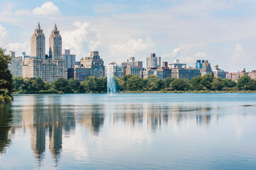 Fototapeta na wymiar Central park lake view of New York City skyline in summer. USA travel vacation destination, reflection of buildings in water.