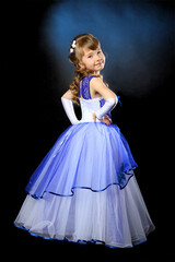 A girl in a ball gown on a dark background is turned back.