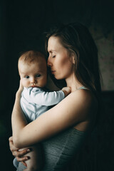 Mom hug the baby standing at the window, mom's weekdays