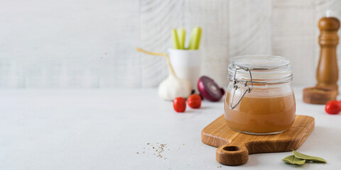 Bone broth soup in glass jar for storage on a wooden board. The concept of healthy eating. Copy space.