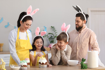 Happy family in bunny ears with Easter cakes at home