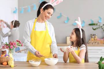 Little girl with her mother cooking in kitchen on Easter day