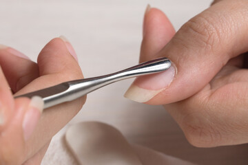 Manicure. Push back the cuticle with a metal pusher. Getting injured during a manicure. Skin care, hygiene. Spa, nail salon. Home care. Beauty. - obrazy, fototapety, plakaty