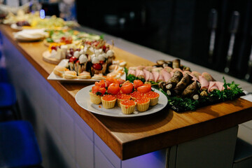 Meal. Festive buffet table for guests. Assortment of cold cuts,canapes on wooden skewers, festive snacks with fruits and salads. Reception at the party.