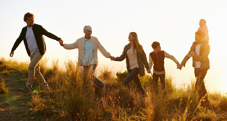 The hills are alive. Shot of a happy family holding hands on a morning walk together.