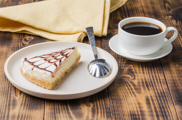 Cheesecake on a white plate with a cup of coffee