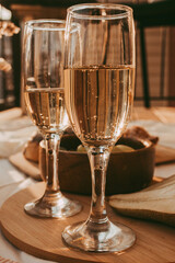Two glasses of white wine on a wooden tray with fruits at sunset.