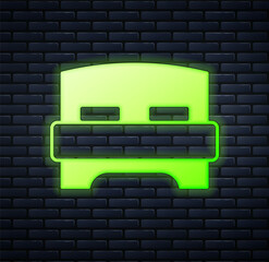Glowing neon Big bed for two or one person icon isolated on brick wall background. Vector