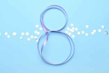 Figure 8 made of ribbon and confetti on color background. International Women's Day celebration