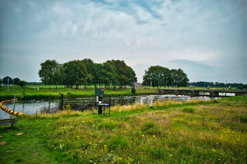 Drone view of the river Vecht, green grass, trees, beautiful blue sky and cycle path through the Vecht valley. Bridge and weir in the river. Dalfsen Netherlands
