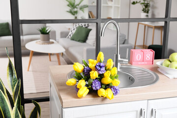 Kitchen counter with cube calendar and bouquet of flowers in sink. International Women's Day celebration